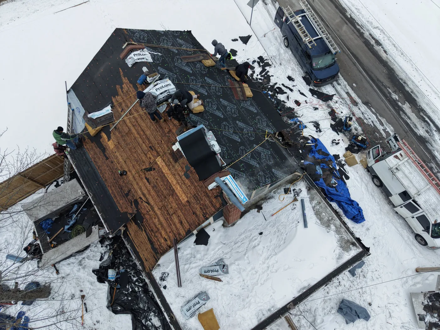 GNG Roofing crew installing a new roof in winter, drone view